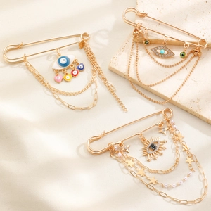 Detailaufnahme goldener Sicherheitsnadel-Broschen mit Evil Eye und Herzanhängern