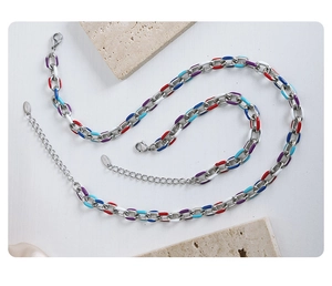 Flat lay of colorful enamel drip titanium steel necklace on marble and silk backdrop