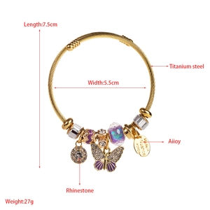 Dettaglio del bracciale in acciaio titanio dorato con farfalla viola e ciondoli strass