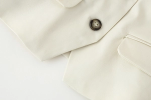 Close-up of beige twill fabric vest showing premium texture, button, and pocket detail
