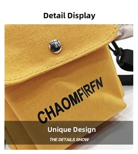 Detail of yellow canvas crossbody bag featuring black letter embroidery and silver metal snap