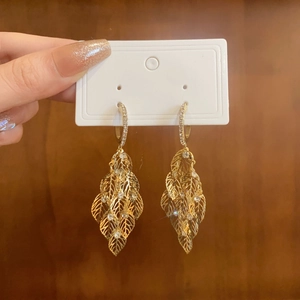 Detailed view of long gold tassel earrings with hollow leaf shape and inset crystals