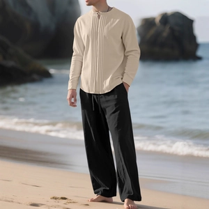 Ensemble chemise beige en lin et pantalon noir pour homme sur une plage ensoleillée