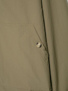 Detail of olive green twill jacket featuring stitching and amber-textured button