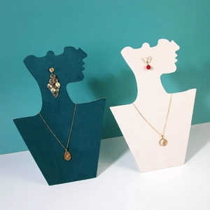 Green and cream profile silhouette jewelry stands displaying gold necklaces and earrings