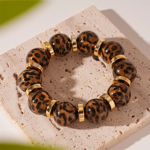Detailed macro view of leopard print acrylic beads and golden metal spacers on a bracelet