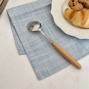 Tovaglietta in cotone e lino a quadretti blu con un cucchiaio in legno e pasticceria