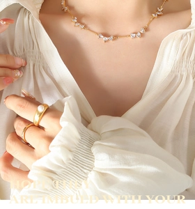 Detail of gold heart zirconia necklace and pearl ring on model in white shirt