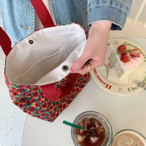 Detailed close-up of corduroy floral tote bag featuring red wide strap and magnetic buckle