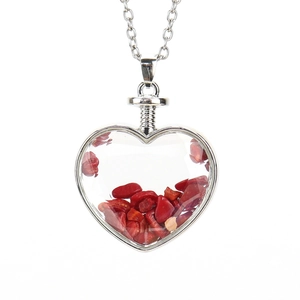 Detail of a heart-shaped pendant with red gravel stones and a silver metal chain