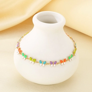 Detail of gold chain anklet with colorful enamel butterflies on a white ceramic vase