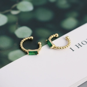 Detailed shot of gold plated s925 silver clip-on earring with green emerald zircon
