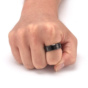 Minimalist black tungsten ring with parallel grooves worn by a man in a fist pose
