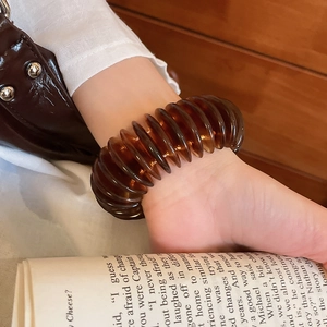 Brown translucent spiral bracelet on wrist with a minimalist white shirt background