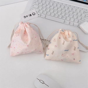 Close-up of cute cartoon drawstring pouches in pink and beige on a tidy office desk