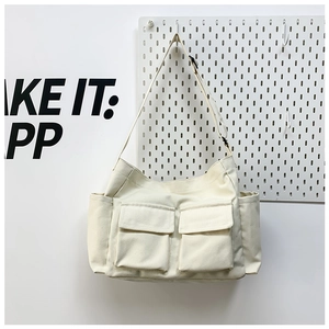 Detail of off-white canvas crossbody bag featuring functional dual front pockets