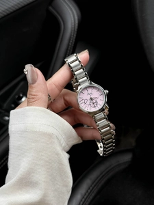 Detail of pink floral dial quartz watch with silver steel strap on wrist in car
