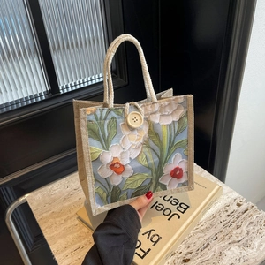 Detail of linen tote bag featuring vintage floral patterns and woven handles