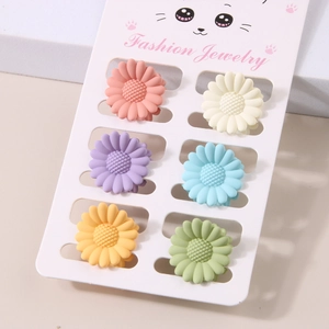 Detail of 6-piece daisy hair clips in matte macaron colors on a white display card