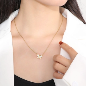 Close-up of a gold butterfly pendant necklace with sparkling stones on a model's neck
