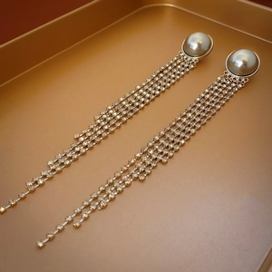 Detail view of pearl and rhinestone tassel earrings with multi-layered golden chains