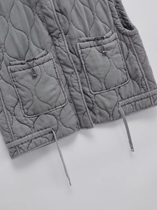 Close-up of grey quilted vest featuring drawstring pockets and adjustable hem detail