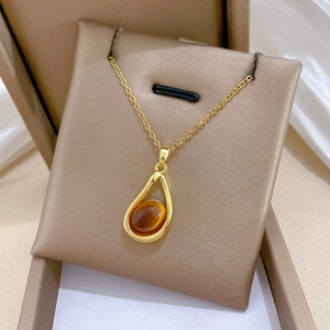 Detail of amber gemstone water-drop pendant on gold-plated necklace with sparkling stones