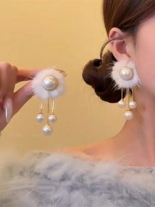 Détail de boucles d'oreilles d'hiver avec fourrure blanche et pampilles de perles dorées