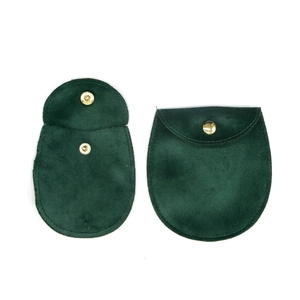 Detail view of dark green velvet jewelry pouches with gold snap button closure and flap