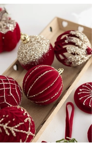 Détail de boules de Noël en velours rouge avec broderies dorées et détails scintillants
