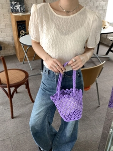 Detail of hand-woven purple bucket bag in a lifestyle cafe setting showing craftsmanship