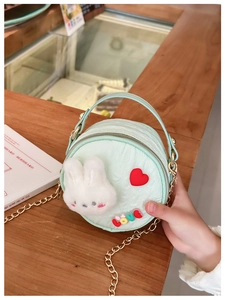 Détail du sac rond vert menthe avec peluche lapin, patch amour et bandoulière chaîne