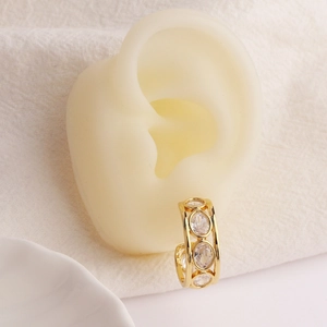 Ear cuff a forma di C placcato oro con cuori in zircone su un modello di orecchio in silicone
