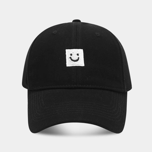 Gros plan sur la casquette en coton noir avec un écusson brodé d'un smiley blanc