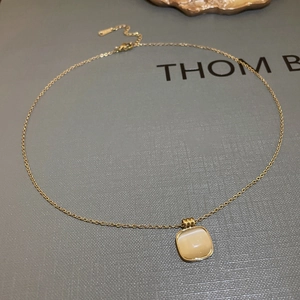Détail d'une chaîne en titane doré avec pendentif carré en oeil-de-chat et fermoir homard