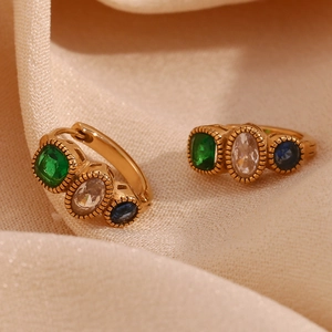 Macro detail of 18K gold earrings with blue, green, and white sapphire gemstones