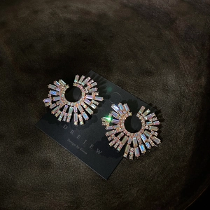 Macro shot of iridescent rhinestone fan earrings on black display card with gold finish
