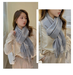 Detail of grey plaid cashmere-like scarf with soft tassels and woven check texture