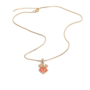 Detail of gold crown pendant with sparkling zircons and a vibrant red diamond-shaped drop