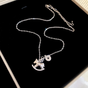Macro detail of silver rocking horse pendant with coins on a black velvet jewelry box