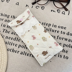 Detail of quilted cartoon glasses pouch with lace trim and heart button on canvas