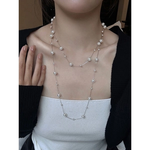 Double-layered pearl necklace with silver chain shown as an elegant sweater chain on a model