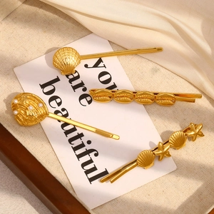 Detailed view of four-piece gold marine hair clips featuring shells, starfish and pearls