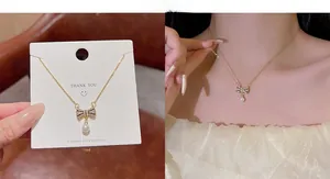 Detail of gold bow necklace with rhinestones and pearl drop on a jewelry card