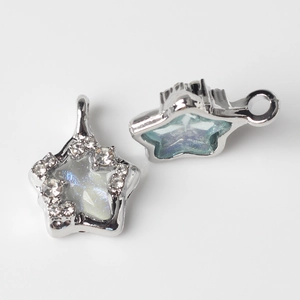 Macro shot of silver star charms with sparkling zircon edges and iridescent resin inlay