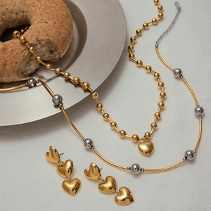 Détail d'un ensemble de bijoux coeur or et argent posé sur un fond de tissu blanc