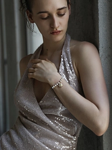 Detailed view of an 18K gold-plated pearl bracelet with shell charm on a model wrist