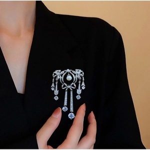 Broche nœud argentée avec perles et pompons en zircon sur une veste de blazer