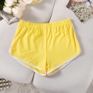Detailed view of yellow yoga shorts with white trim laid on a clean white background
