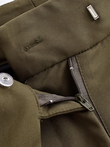 Detail view of olive green wide leg trousers showing metal hook, button and YKK zipper